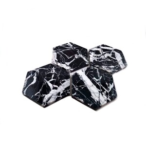 May include: Set of four black and white marble hexagon coasters. The coasters have a natural veined pattern.