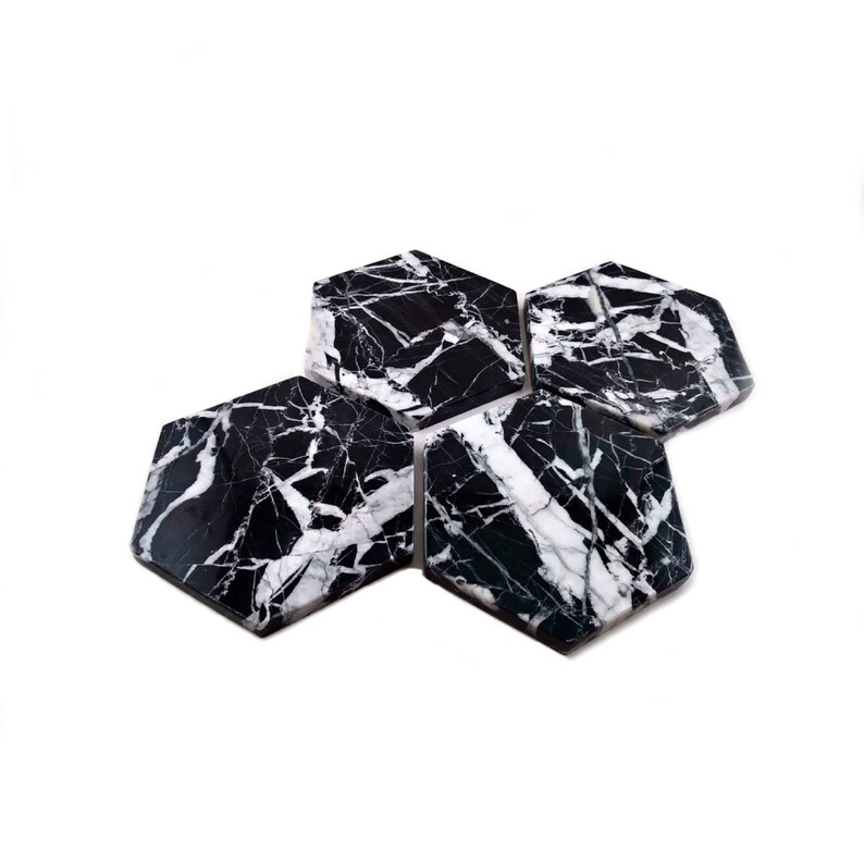 May include: Set of four black and white marble hexagon coasters. The coasters have a natural veined pattern.