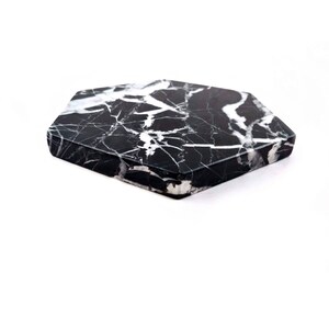 May include: Black and white marble hexagon coaster. The coaster has a smooth, polished surface.