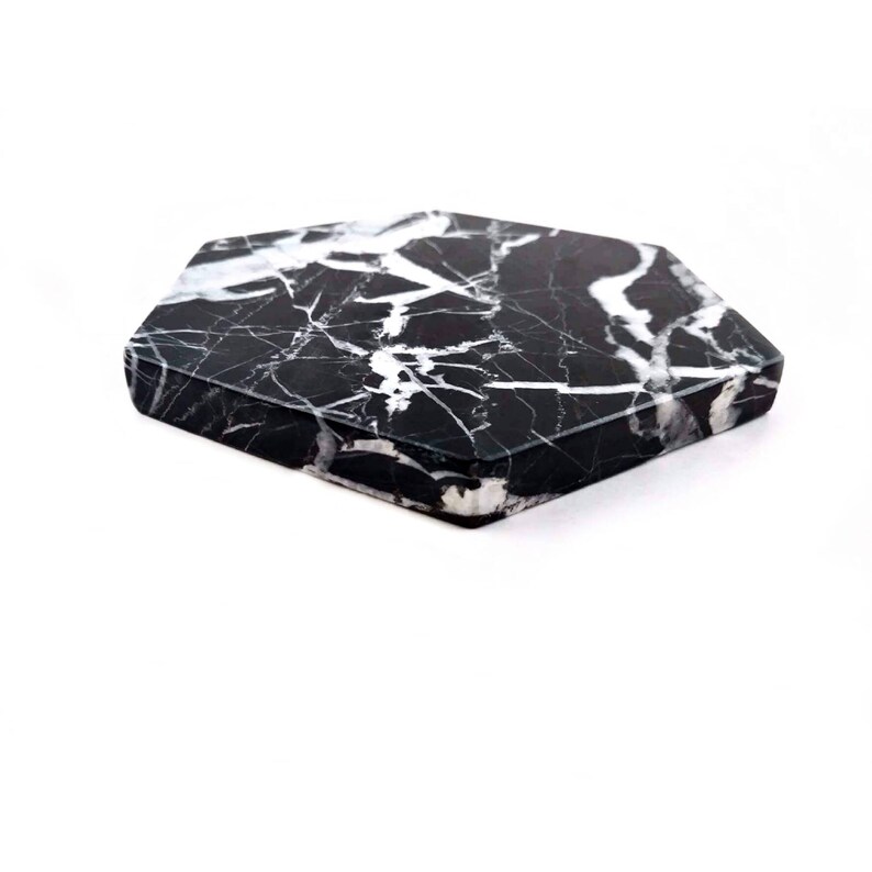 May include: Black and white marble hexagon coaster. The coaster has a smooth, polished surface.
