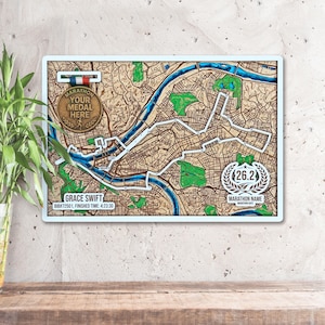 Peut inclure: Une carte en bois d'un parcours de marathon, avec un porte-médaille. La carte comprend le texte "MARATHON YOUR MEDAL HERE", "26.2" et "MARATHON NAME". Le nom "GRACE SWIFT" et les détails de la course sont également visibles.