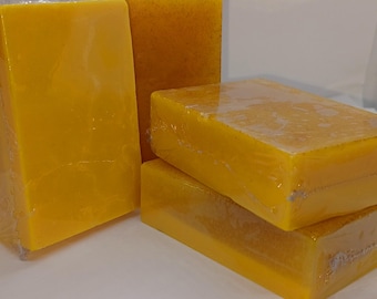 May include: Four bars of yellow soap wrapped in plastic. The soap is a bright yellow colour and has a grainy texture.