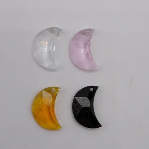 May include: Four crystal moon shaped charms in different colors: clear, pink, yellow, and black.