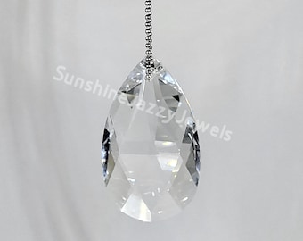 May include: A clear crystal teardrop pendant hangs from a silver chain. The pendant is faceted and reflects light.