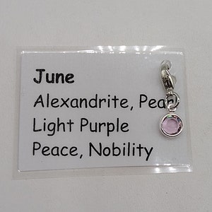 May include: June birthstone charm with a light purple Alexandrite gemstone. The charm is silver and has a text card that reads "June, Alexandrite, Pear, Light Purple, Peace, Nobility".