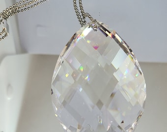 May include: A clear crystal teardrop pendant with a silver chain. The crystal has a faceted design and catches the light, creating rainbows.