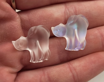 May include: Two iridescent glass cat figurines. The cats are in a sitting position with their tails curled around their bodies. The glass is clear and has a slight iridescent sheen.