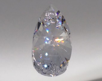 May include: A clear crystal teardrop pendant with a faceted design. The crystal reflects light, creating a rainbow effect.