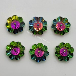 May include: Six iridescent green flower-shaped buttons with a pink center. The buttons have a faceted design and a hole in the center.