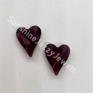 May include: Two purple heart-shaped glass beads with a striated pattern.
