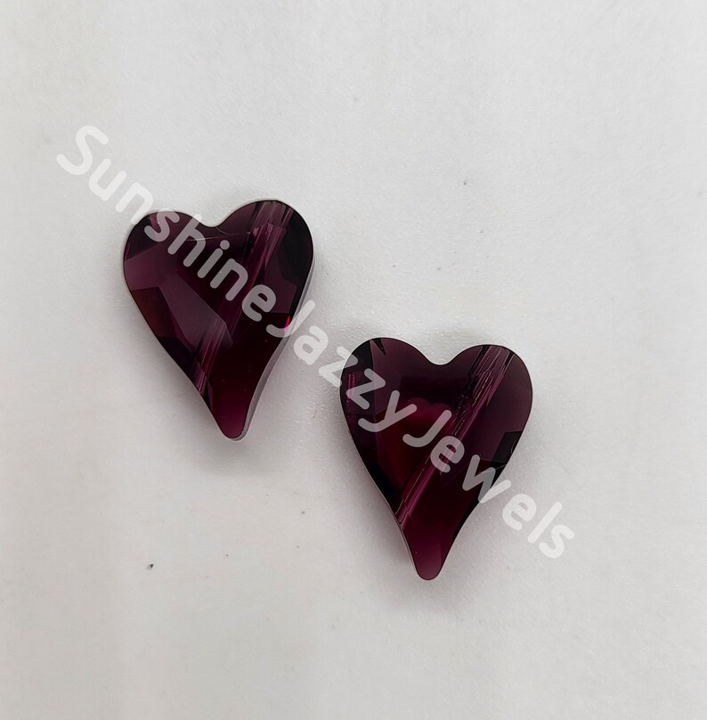May include: Two purple heart-shaped glass beads with a striated pattern.