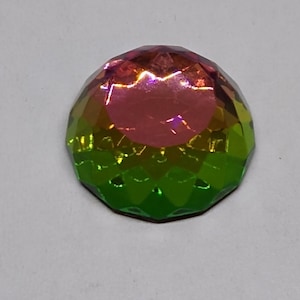 May include: A multi-faceted iridescent gemstone with a pink, yellow, and green color gradient.