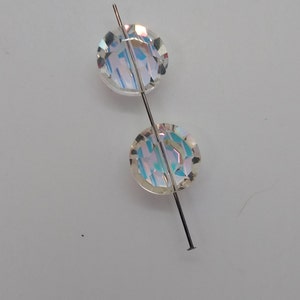 K&ouml;nnte beinhalten: Zwei irisierende, klare Glasperlen, die auf einem silbernen Draht aufgef&auml;delt sind.