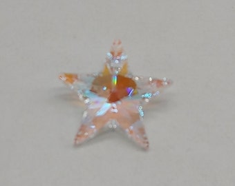 May include: A clear iridescent star-shaped crystal charm with a light orange hue.