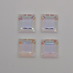 May include: Four iridescent square-shaped rhinestones with a beveled edge.