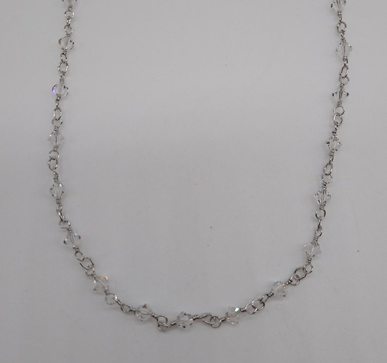 K&ouml;nnte beinhalten: Eine silberne Kettenkette mit klaren Kristallperlen.