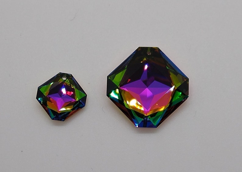Puede incluir: Dos prismas de cristal octogonales iridiscentes con un agujero en la parte superior para colgar. El prisma m&aacute;s grande es de color morado oscuro con acentos verdes y dorados. El prisma m&aacute;s peque&ntilde;o es de color morado m&aacute;s claro con acentos rosados y naranjas.