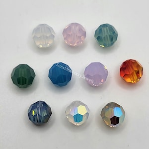 May include: A collection of faceted crystal beads in various colors, including white, pink, teal, green, blue, purple, and orange. The beads are round and have a multi-faceted design, reflecting light. The text "Sunshine Jazzy Jewels" is visible.
