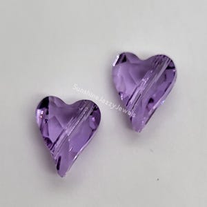 K&ouml;nnte beinhalten: Zwei violette herzf&ouml;rmige Glasperlen mit facettiertem Design.