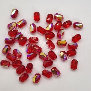 May include: A group of red faceted glass beads with a rectangular shape. The beads have a iridescent finish.