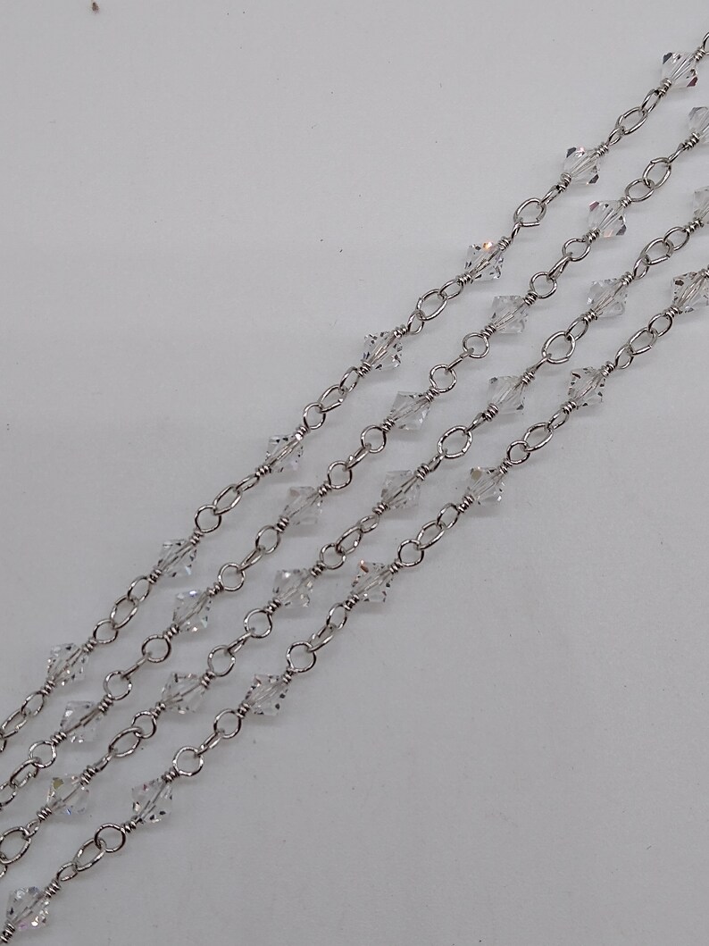 K&ouml;nnte beinhalten: Eine silberne Kette mit klaren Kristallperlen. Die Kette ist geschichtet und hat einen zarten Look.