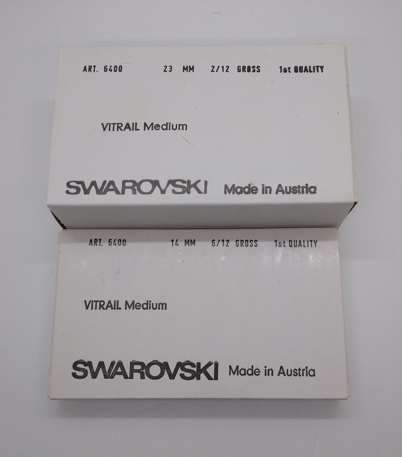 Puede incluir: Dos cajas blancas con texto negro. La caja superior dice "ART. 6400 23 MM 2/12 GROSS 1st QUALITY VITRAIL Medium SWAROVSKI Made in Austria". La caja inferior dice "ART. 6400 14 MM 6/12 GROSS 1st QUALITY VITRAIL Medium SWAROVSKI Made in Austria".