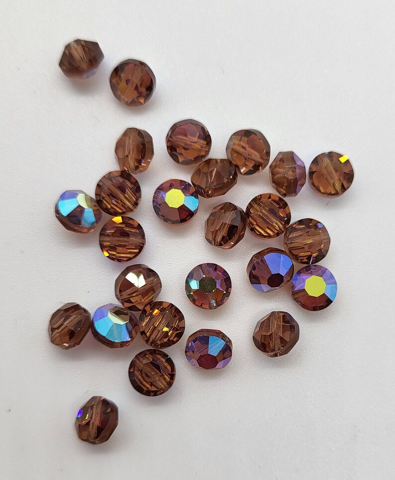 May include: A collection of brown iridescent glass beads. The beads are round and have a faceted design.