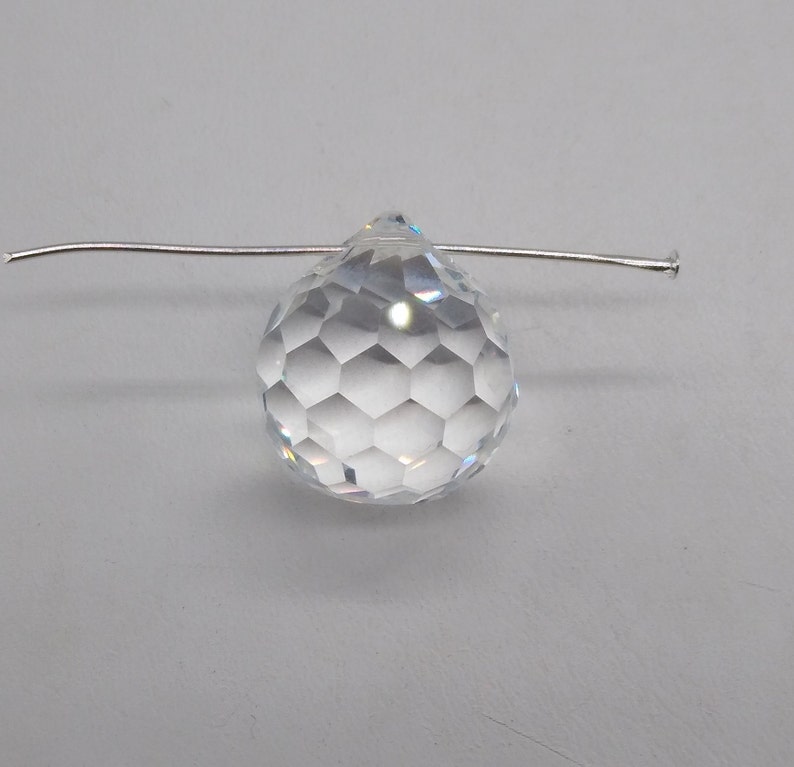 May include: A clear crystal teardrop prism with a faceted design, hanging from a silver wire.