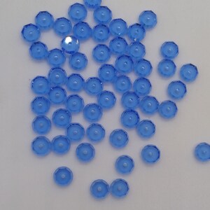 May include: A scattering of light blue, faceted, round glass beads with a hole in the center.