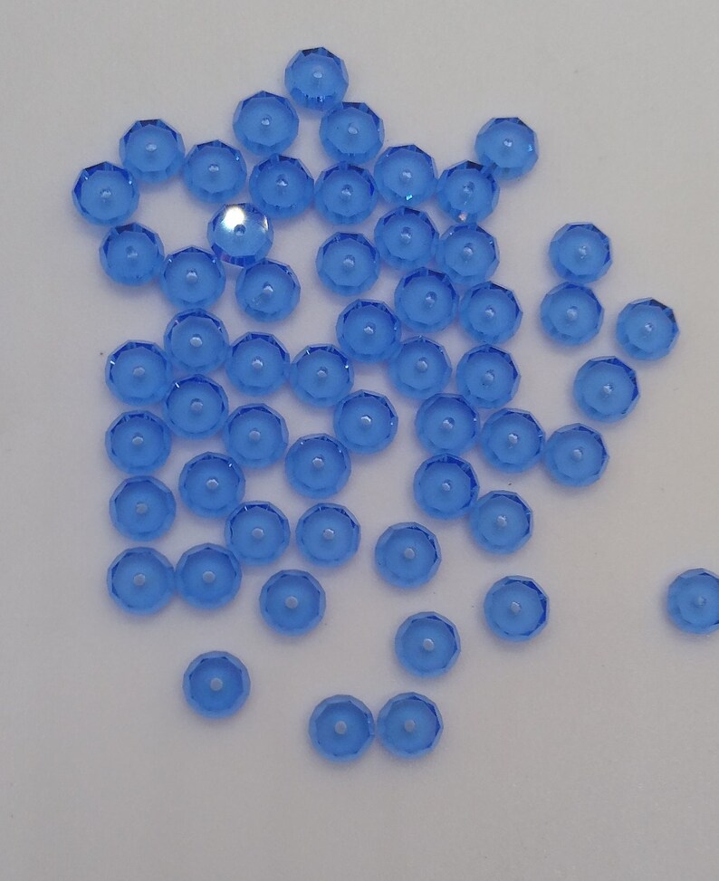 May include: A scattering of light blue, faceted, round glass beads with a hole in the center.