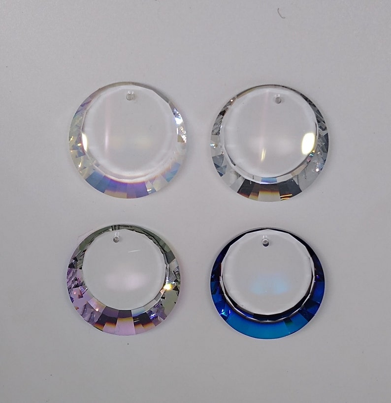 May include: Four crystal suncatchers with a round shape and a hole at the top. Two are clear, one is iridescent purple, and one is iridescent blue.