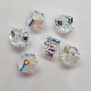 May include: Six iridescent clear glass cube beads with a hole through the center. The beads have a rainbow effect and are perfect for jewelry making.