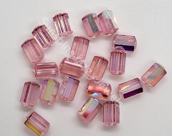 Può includere: Una collezione di perline di vetro rettangolari sfaccettate di colore rosa iridescente. Le perline hanno un leggero luccichio e sono perfette per la creazione di gioielli.