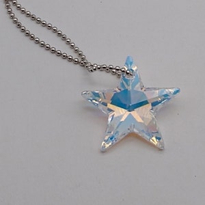 May include: A silver chain necklace with a clear iridescent star-shaped crystal pendant.