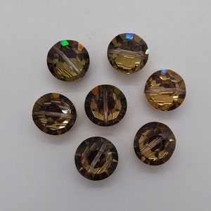 May include: Seven round, faceted, iridescent glass beads in shades of brown and gold. The beads have a hole through the center for stringing.