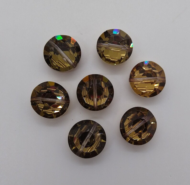 May include: Seven round, faceted, iridescent glass beads in shades of brown and gold. The beads have a hole through the center for stringing.