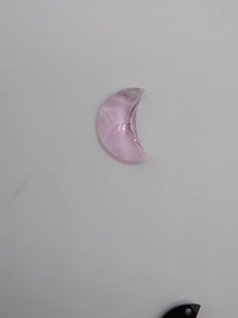 May include: A light pink crystal crescent moon charm with a hole at the top for hanging.