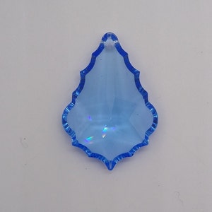 May include: A light blue crystal teardrop pendant with a faceted design. The pendant has a hole at the top for hanging.