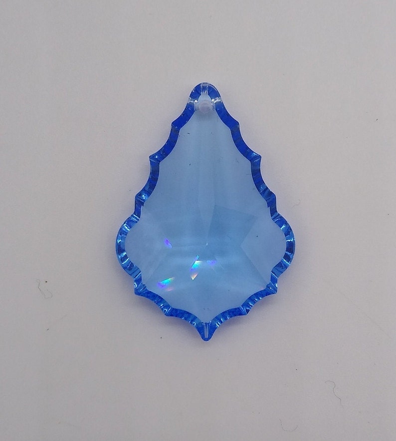 May include: A light blue crystal teardrop pendant with a faceted design. The pendant has a hole at the top for hanging.