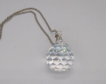 May include: A silver chain necklace with a clear crystal pendant. The pendant is a faceted ball with a silver bail.