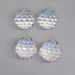 May include: Four clear crystal faceted teardrop shaped pendants with a hole at the top for hanging.
