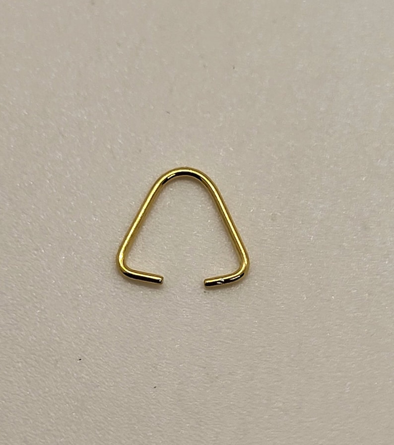 May include: A gold triangle jump ring, a small metal loop with a triangular shape, used for connecting jewelry components.