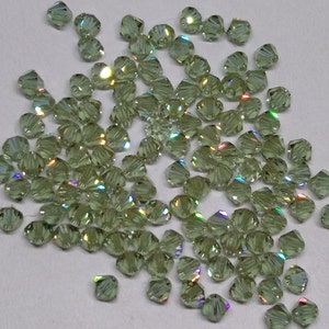 May include: A large quantity of small, iridescent green glass beads. The beads are faceted and have a slightly rounded shape.