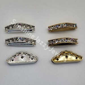 May include: Two sets of shoe buckles, one silver and one gold. Each set includes two pieces: a curved piece with a row of clear rhinestones and a triangular piece with three holes.