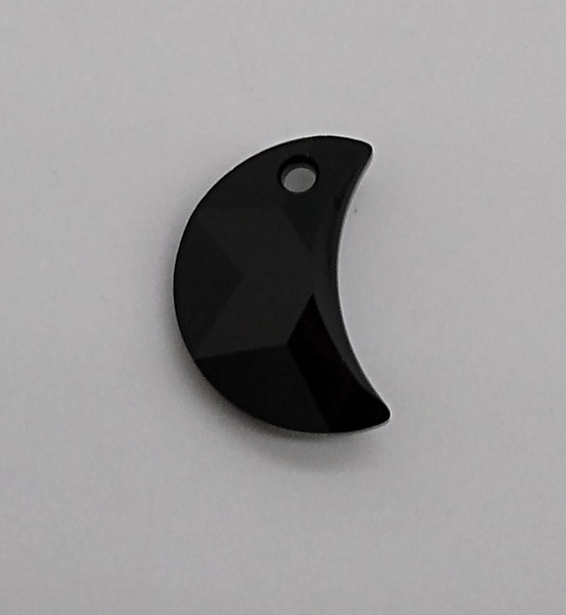 May include: Black crescent moon shaped crystal charm with a small hole at the top for hanging.