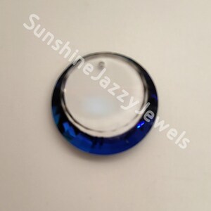 May include: A round, clear glass pendant with a blue, iridescent border. The pendant has a hole at the top for hanging.