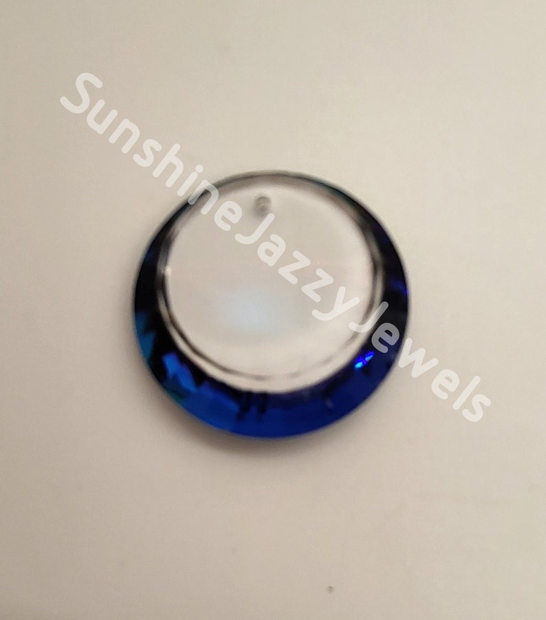 May include: A round, clear glass pendant with a blue, iridescent border. The pendant has a hole at the top for hanging.