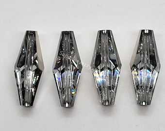 May include: Four clear glass beads with a faceted, teardrop shape. The beads have a silver iridescent finish.