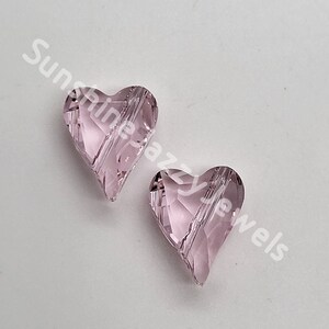 May include: Two pink glass heart-shaped beads with a faceted design. The beads are approximately 1 inch in size.