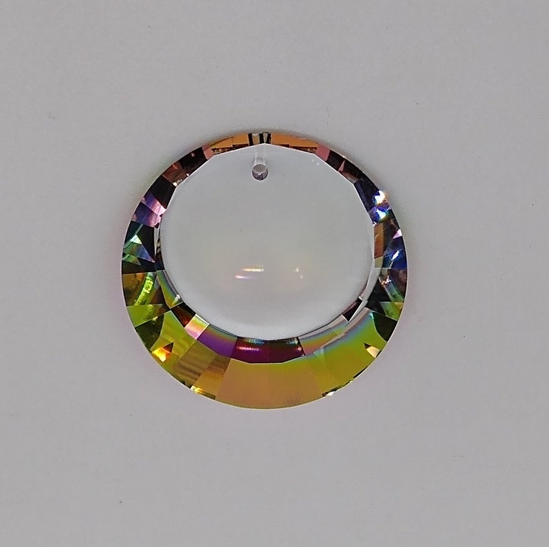 May include: A round, iridescent crystal prism with a hole in the top for hanging. The prism has a rainbow effect with shades of green, yellow, orange, red, purple, and blue.